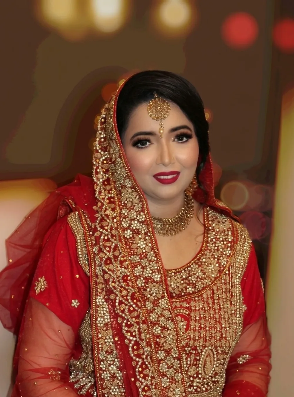 Bride in red and gold with her dupatta pinned and jewellery set by Bridal Art Studio